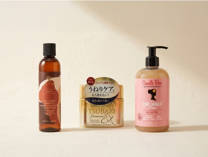 Three hair care products arranged on a warm beige background: a shampoo, hair mask and hair jelly.
