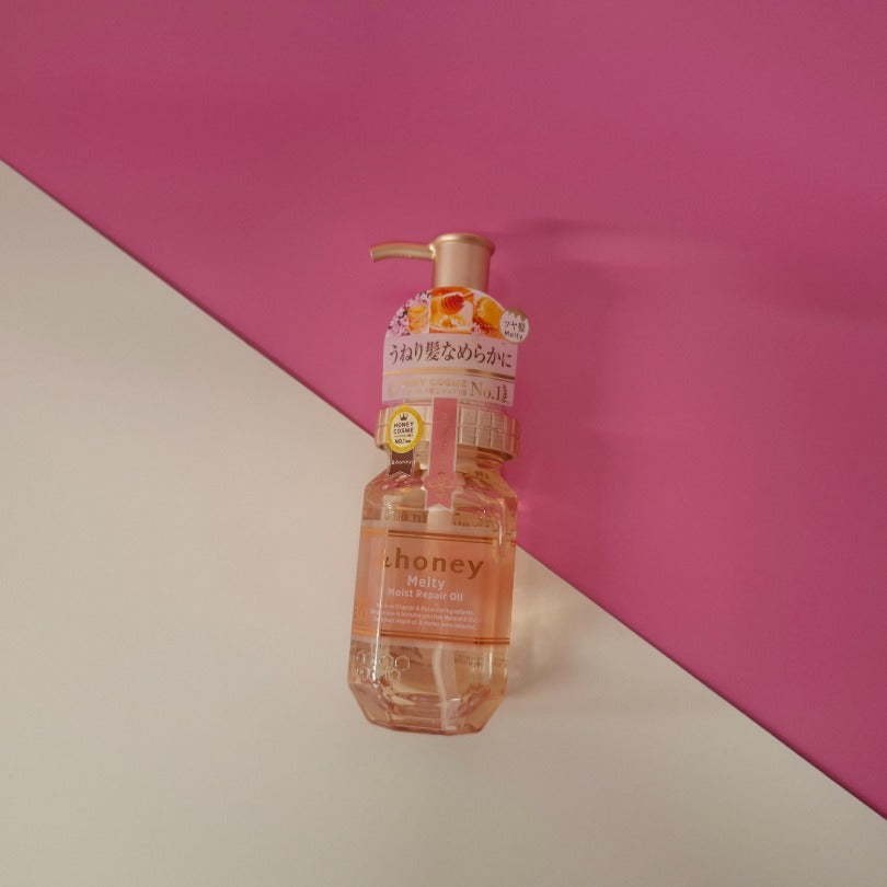 Bottle of &honey melty oil on a pink and beige background