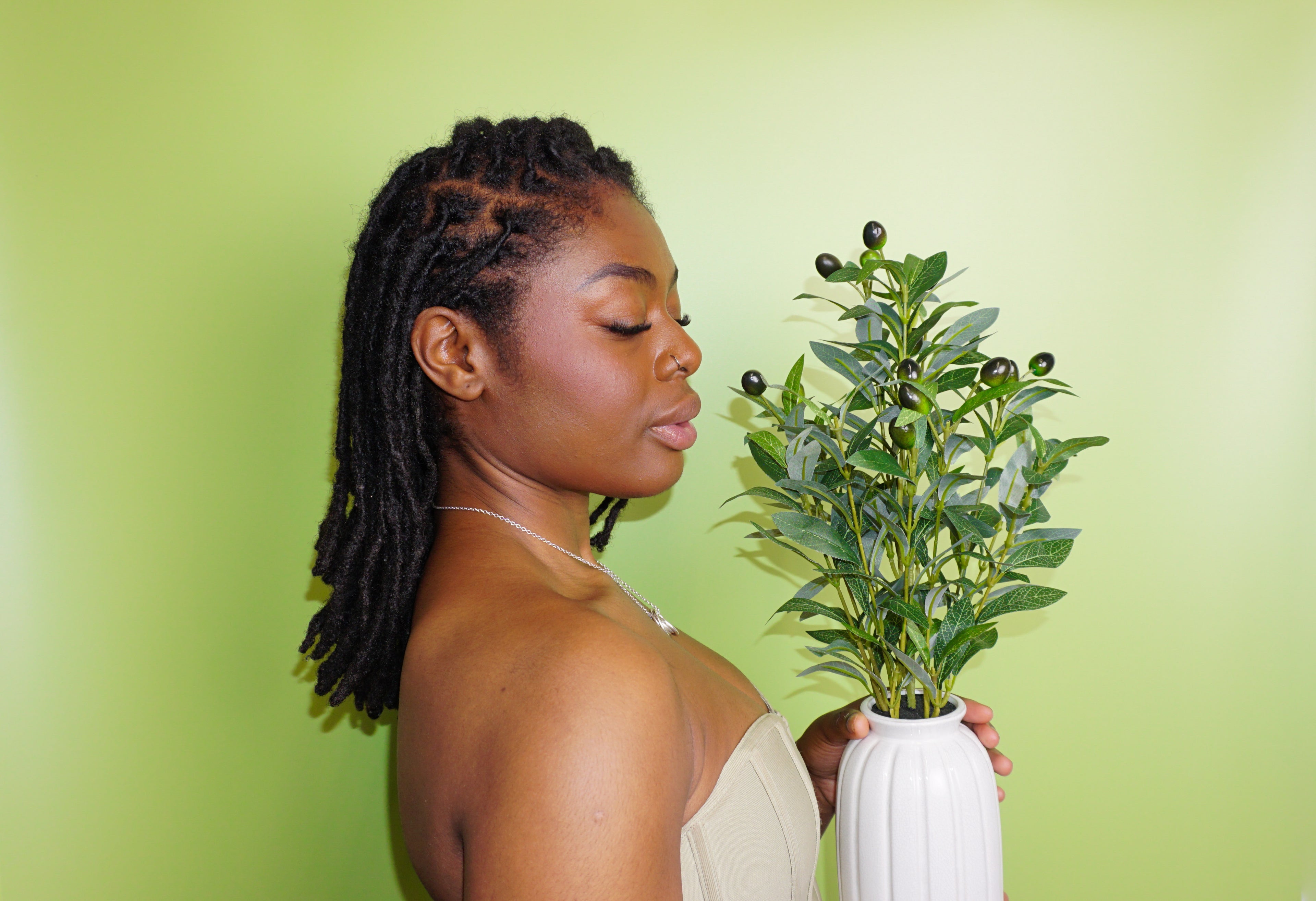 Woman holding a plant against a green background