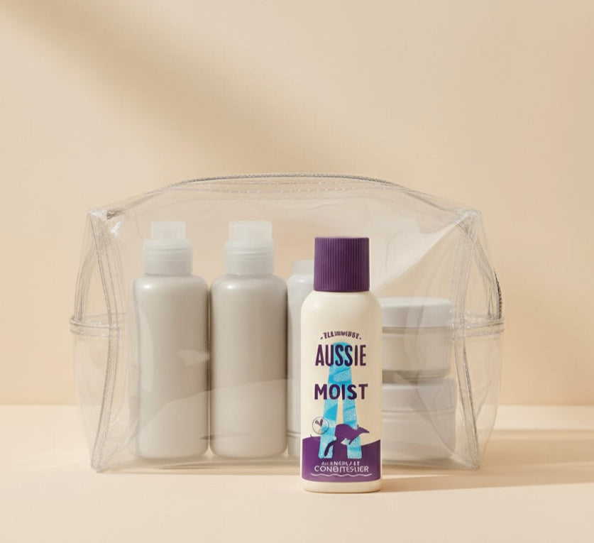 Clear travel pouch with Aussie conditioner and bottles on a beige background