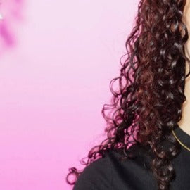 Person with curly hair against a pink background