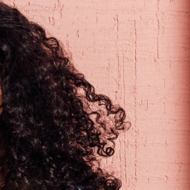 Close-up of curly hair against a textured pink background