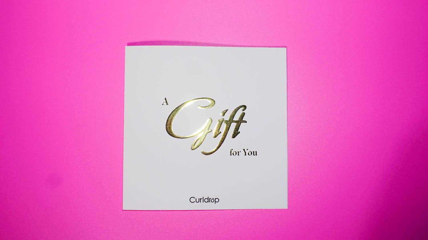 White gift card with gold text on a pink background