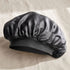 Black satin hair bonnet on a beige background