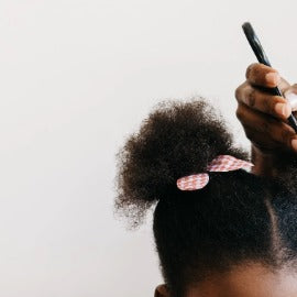Person with curly hair tied up against a plain background
